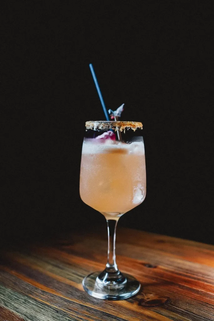 Verre à cocktail avec paille bleue et bord sucré sur table en bois.