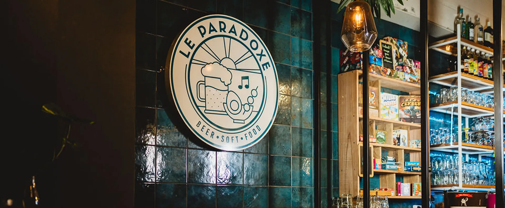 Enseigne "Le Paradoxe" avec étagères de jeux et verres.
