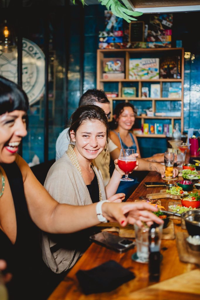 Personnes souriantes partageant un repas et des boissons dans un restaurant convivial.