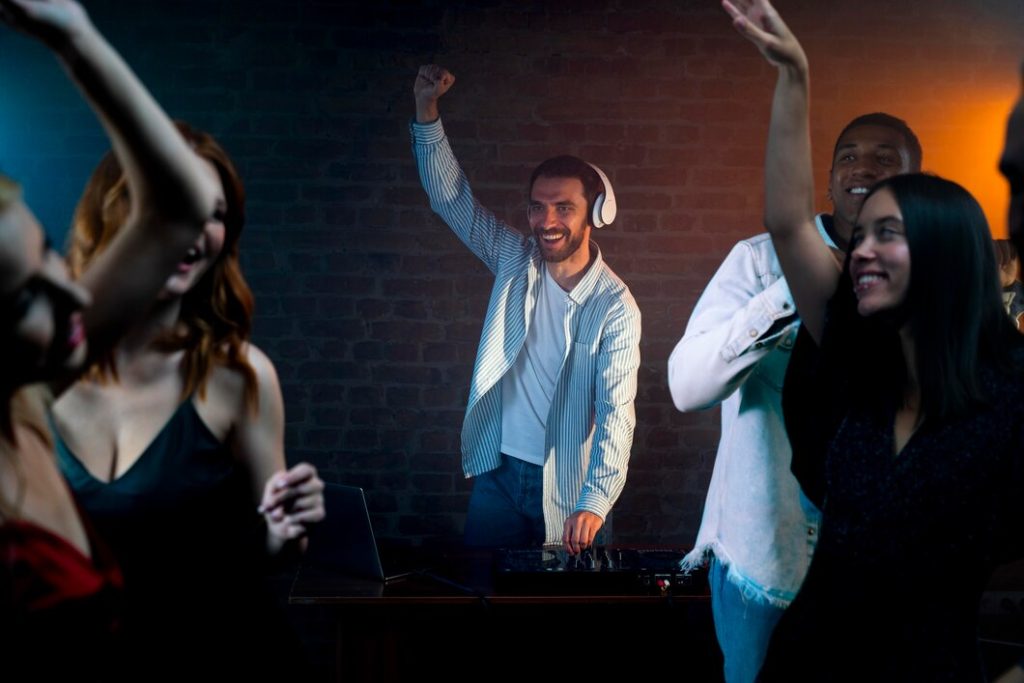 DJ souriant mixant de la musique lors d'une fête animée avec des danseurs.