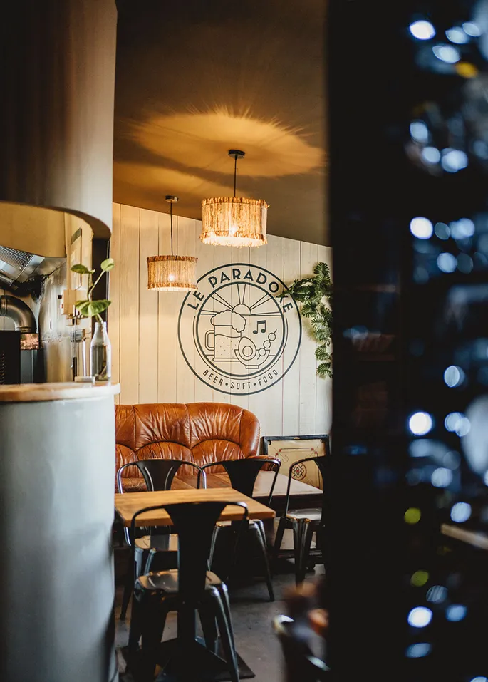 Salon cosy avec logo "Le Paradoxe" sur le mur.